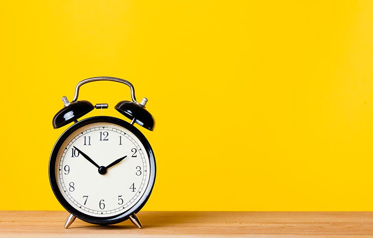 alarm clock on a desk with a yellow background